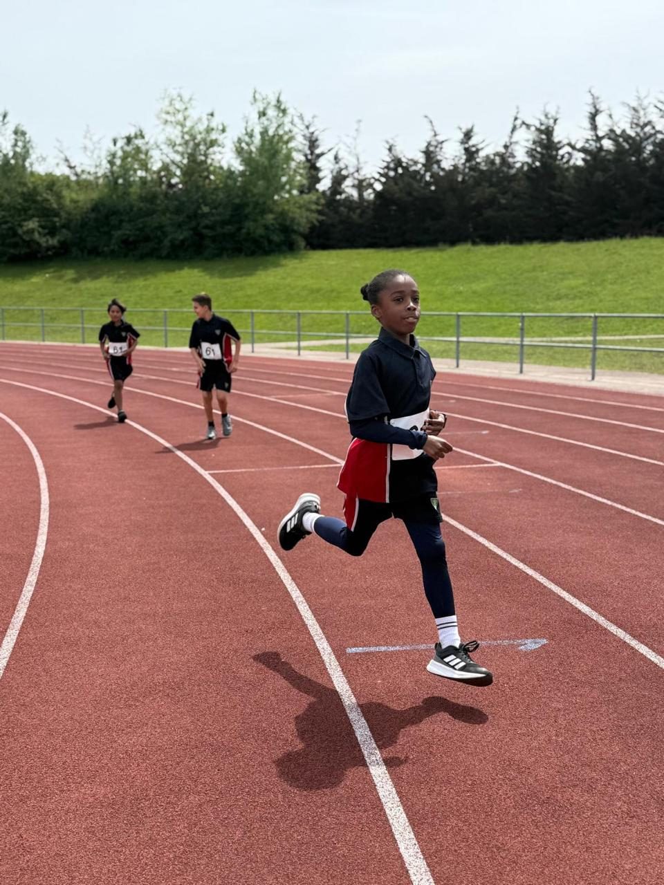A pupil leaps mid-air during a sports day event.