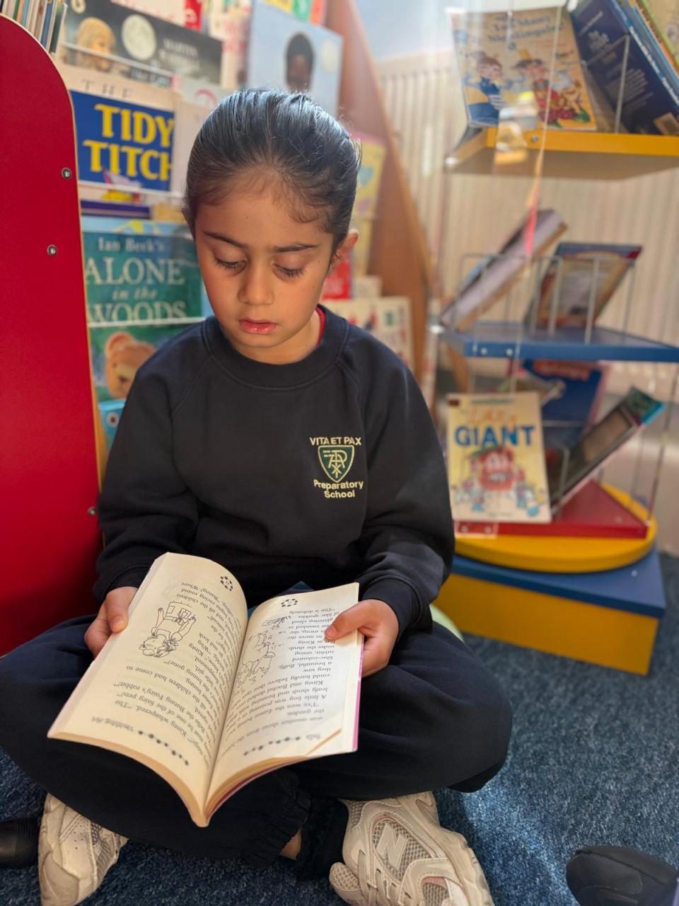 A child reads quietly beneath the school crest in the library.