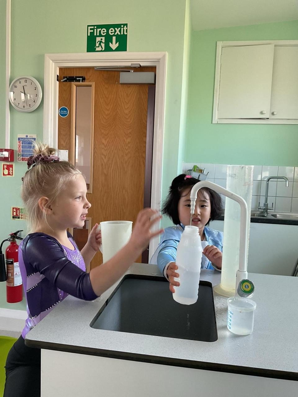 Children measure and pour water in a hands-on science lesson.