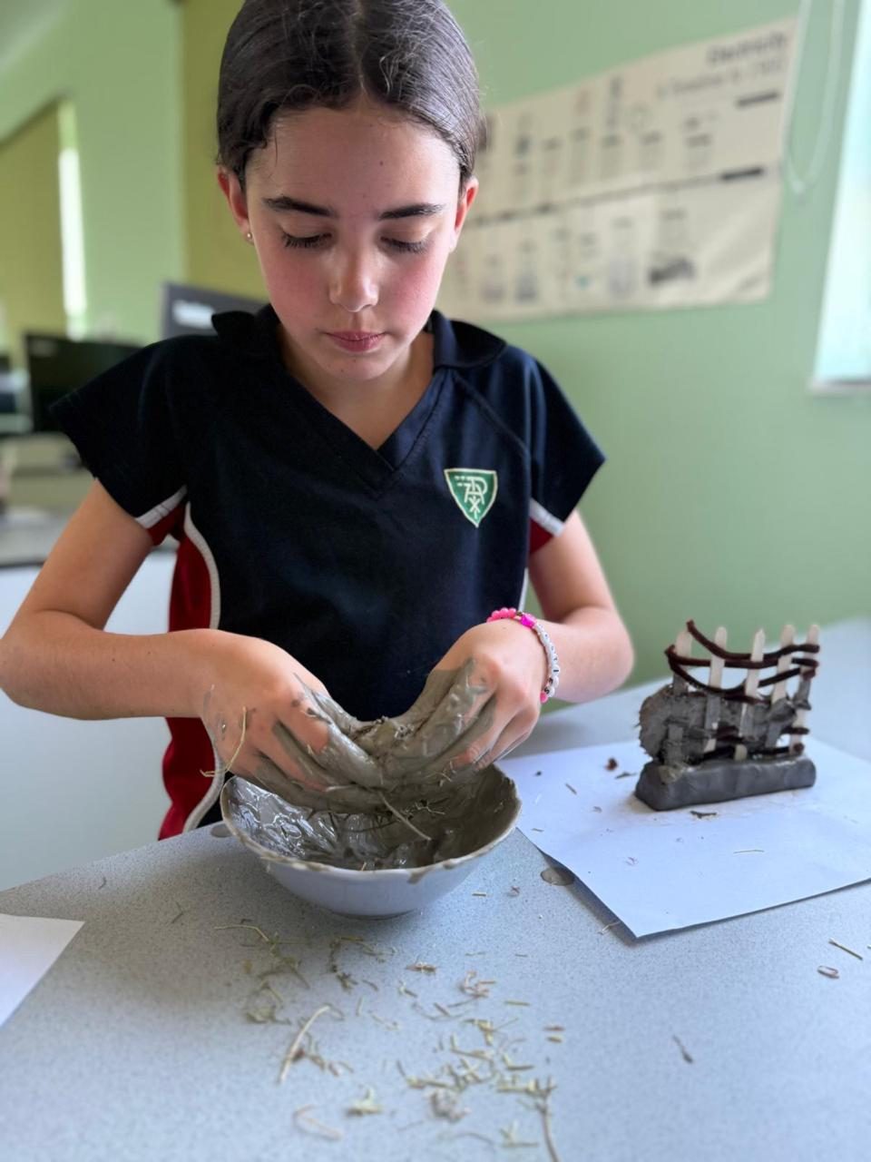 A pupil moulds a clay bowl in an art lesson.
