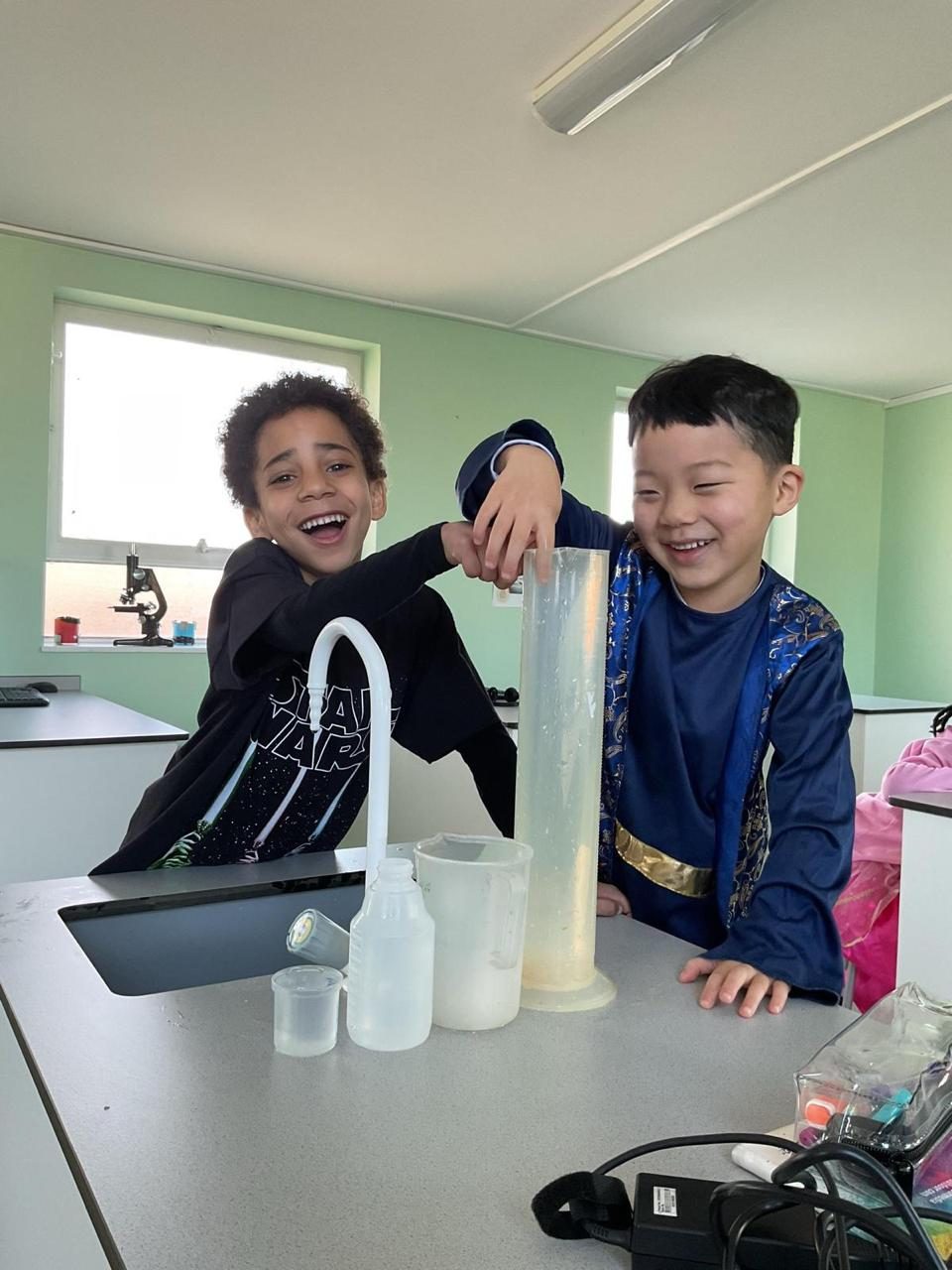Two pupils laugh during a practical science experiment.