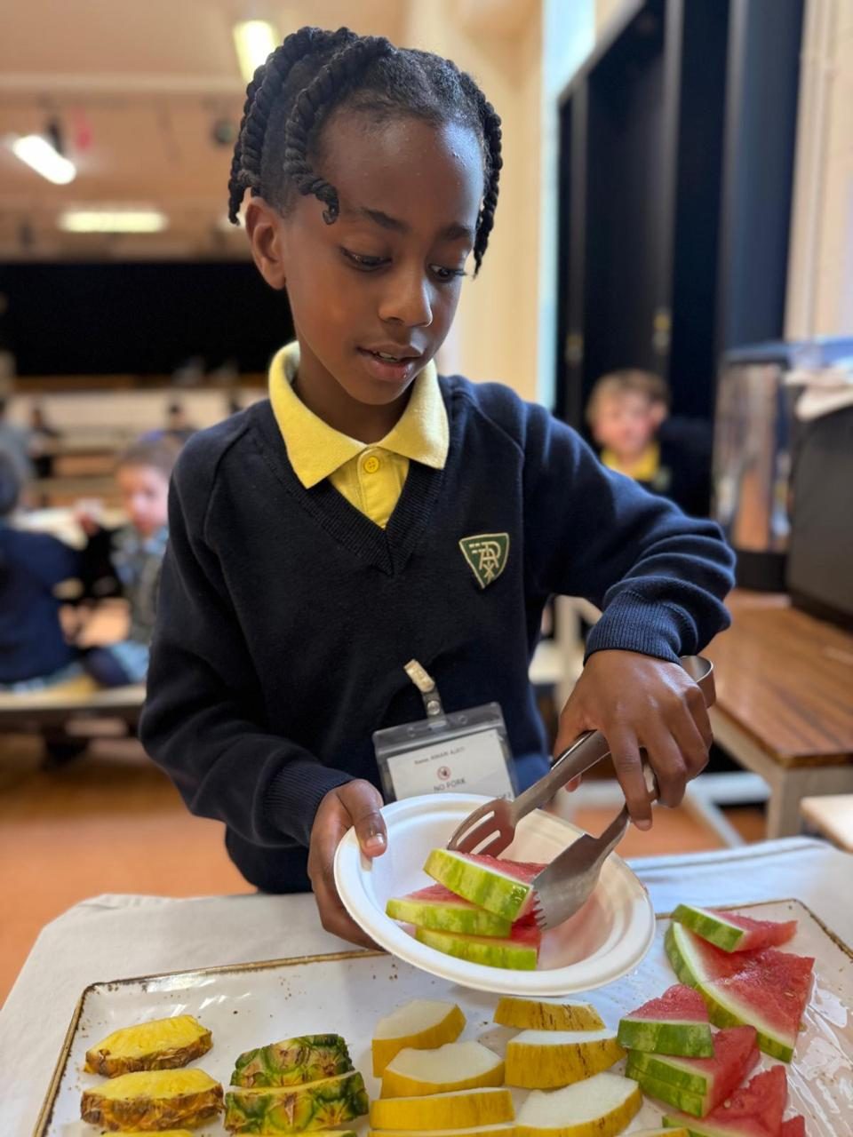 A pupil serves himself fresh fruit at lunchtime.