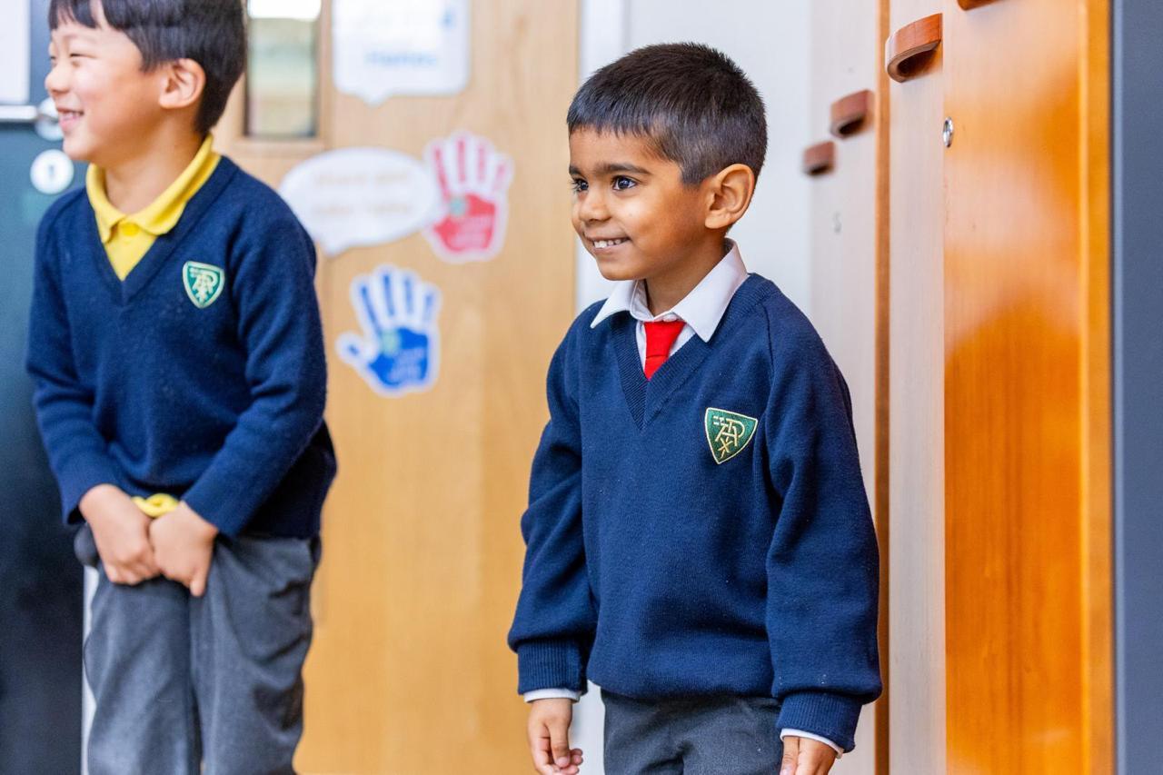Happy Reception pupils in the cloakroom at Vita et Pax Preparatory School, Southgate N14