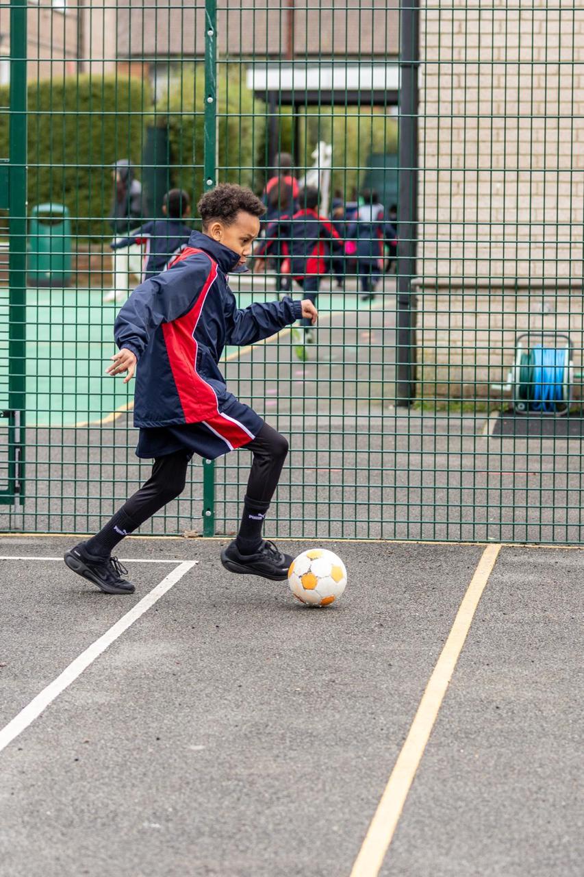 A pupil dribbling a football during games at Vita et Pax, Southgate